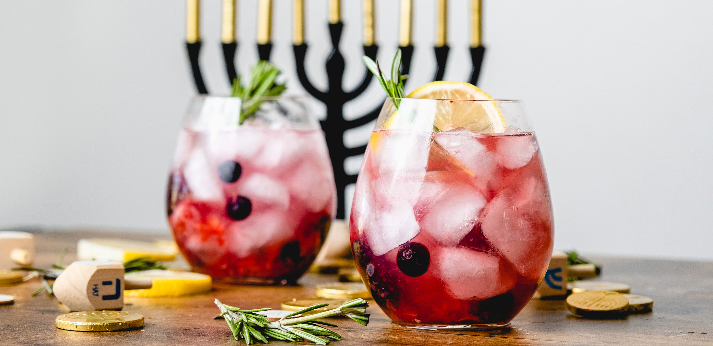 A berry vodka cocktail is seen in front of a Menorah and Dreidel 